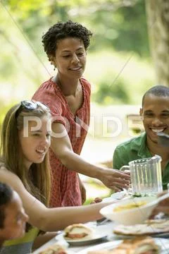 A family gathering, men women and children around a table in a garden in summ Stock Photos