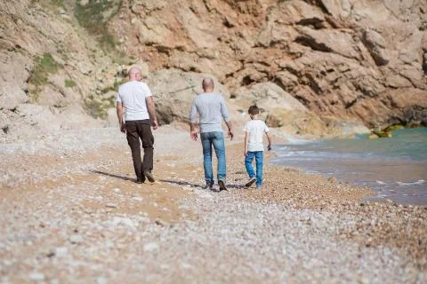 Family of grandfather father and son on a rocky beach on vacation enjoying time Stock Photos