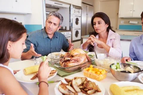 Family having argument sitting around table eating meal Stock Photos