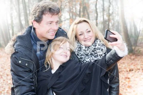 Family, holidays, technology and people concept - smiling mother, father and Stock Photos