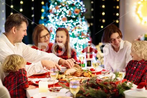 Family with kids having Christmas dinner at tree Stock Photos
