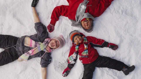 Family laying in winter snow, overhead shot Stock Footage