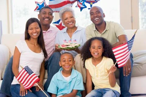 Family in living room on fourth of July with flags and cookies smiling Stock Photos