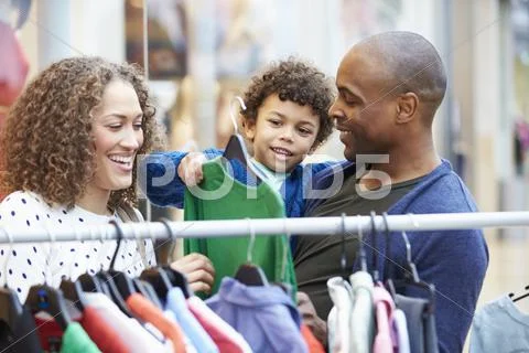 Family Looking At Clothes On Rail In Shopping Mall Stock Photos