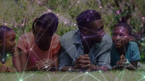 Family lying on grass, talking, man turning toward boy as tech network drifting, Stock Footage 333529009
