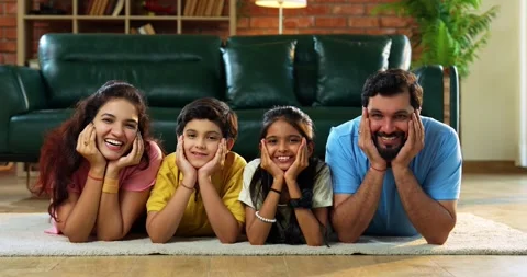 Family lying hands on chin smiling together on carpet looking at camera Stock Footage 342481353
