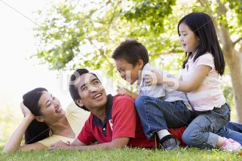 Family lying outdoors being playful and smiling Stock-Fotos