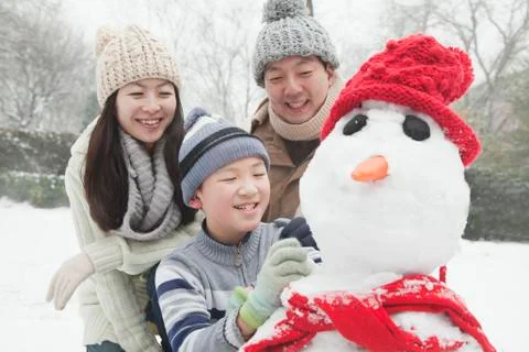 Family making snowman in a park in winter Stock Photos