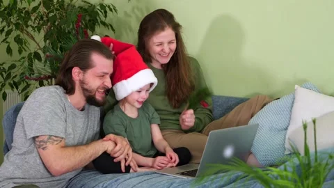 A family for new year in a santa claus cap is ringing a laptop. Quarantine Stock Footage