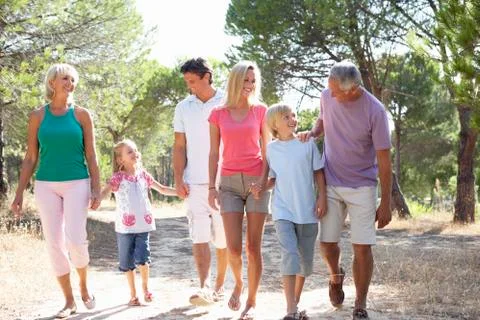 A family, with parents, children and grandparents, walk through park Stock Photos