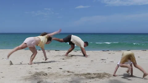 A family performs tricks on a sandy beach. Stock Footage 311052323