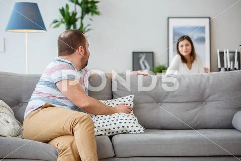 Family photo of man sitting back on couch and wife behind sofa Stock Photos