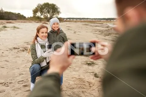 Family photographing by smartphone on autumn beach Stock Photos