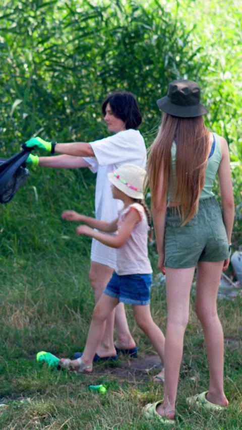 Family play together while collecting litter during a riverbank cleanup campaign Vidéo 340577116