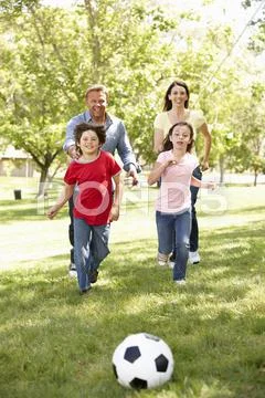Family playing football in park Stock Photos