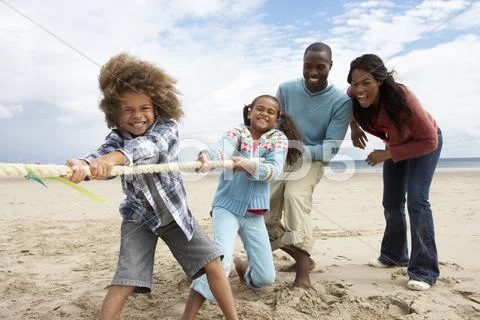 Family playing tug of war on beach Stock Photos