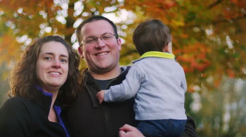 Family posing for a photo in front of tree, baby not looking at the camera Video stock 68898366