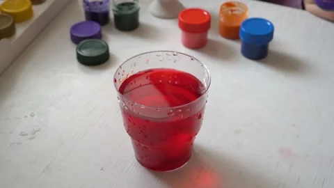 The family is preparing for Easter, the child paints an egg in a glass with red Video stock 103169228