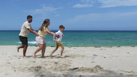 A family pretends to be a train while running on the beach. Stock Footage 311100501