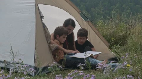 Family reading a book while camping in nature Stock Footage 315994971