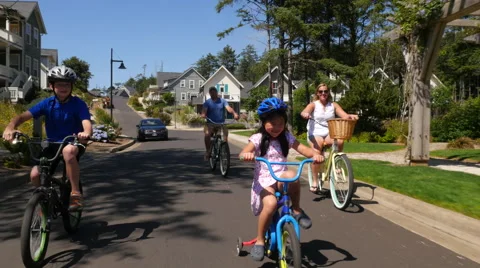 Family riding bicycles together in coastal vacation community Stock Footage