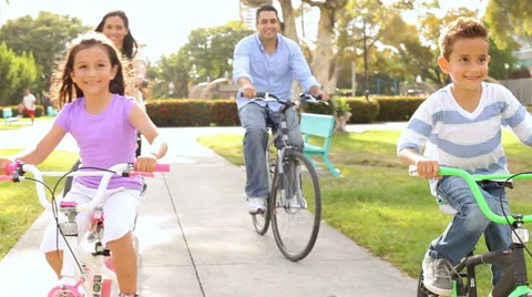 Family Riding Bikes Through Summer Park Stock Footage