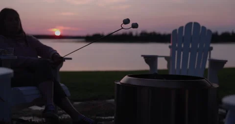 Family roasting marshmallows over firepit in backyard at sunset - relaxation Stock Footage 244905006