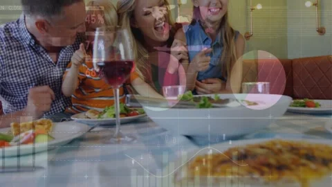 Family sharing dinner in booth, camera pulling back as data charts highlighting Stock Footage 332428587