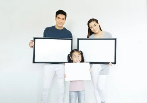 Family showing and holding empty white picture frame over white background. Stock Photos