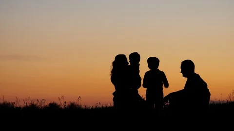 Family silhouettes sitting on hill portr... | Stock Video | Pond5