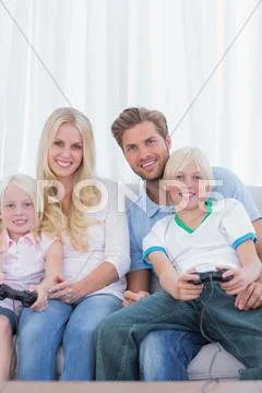 Family sitting on couch playing video games Stock Photos