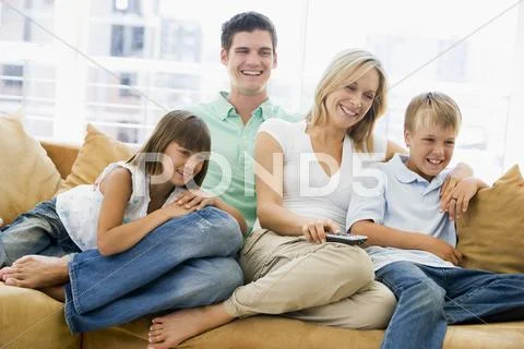 Family sitting in living room with remote control smiling Stock-Fotos