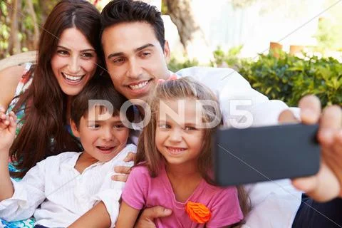 Family Sitting On Seat In Garden At Home Taking Selfie