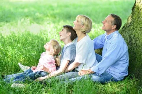 Family sitting in shade under the tree Stock Photos