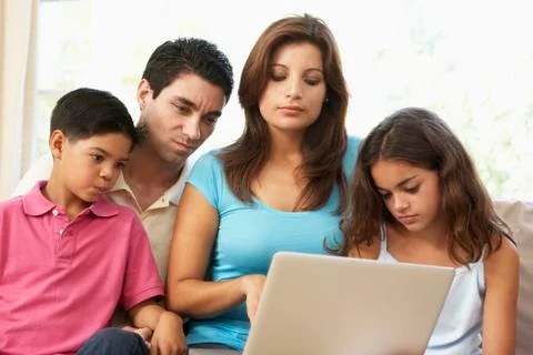 Family Sitting On Sofa At Home With Laptop Stock Photos