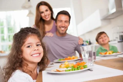 Family smiling at the camera at dinner table Stock Photos