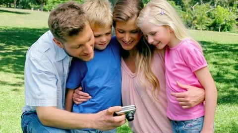 Family smiling while looking at the photo gallery on their camera 库存影片 10816012