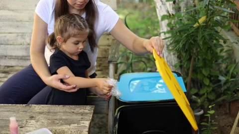 Family sorting garbage at home on backyard. Concept of recycling outdoors. Mom Stock Footage 159803249