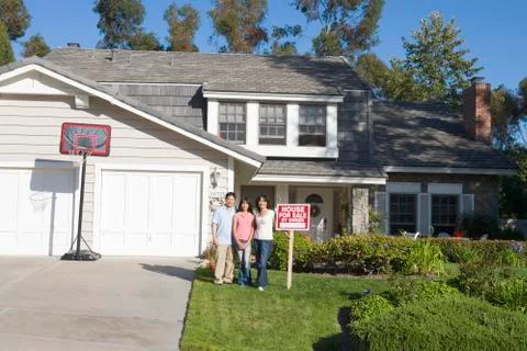 Family Standing Outside House With Real Estate Sign Stock Photos