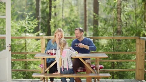 Family of three talking cheerfully while having breakfast in countryside Stock Footage 195355319
