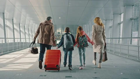 Family of two parents and two kids with luggage walking down the airport Stock Footage 152307989