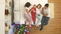 The family unpack gifts on the bed near a christmas tree. view from above 4k or 4k+ Resolution