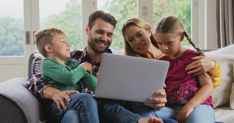 Family using laptop on the sofa in a comfortable home 4k Stock Footage 112040283