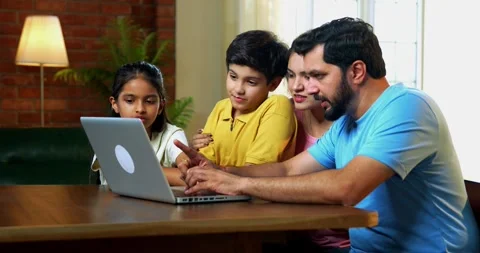 Family using laptop together at dining table while planning vacation Video stock 342487577