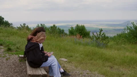 Family using smartphone while relaxing on hill against sky Stock Footage 291500297