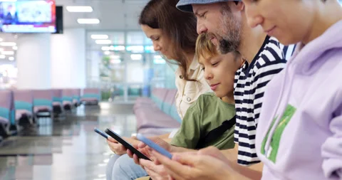 Family using smartphones while waiting at the airport Stock Footage 304070917
