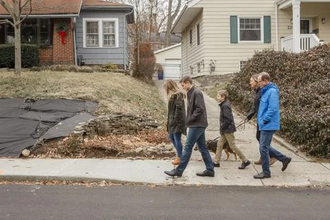 A family walk together with dog through suburban neighborhood Stock Photos