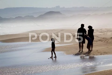 Family walking along foggy beach Stock Photos