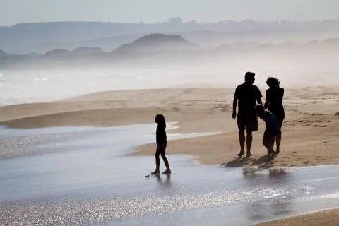 Family walking along foggy beach Stock Photos
