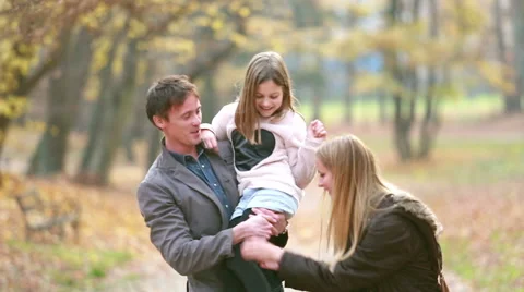 Family walking in park, father carries daughter in his arms and mom tickles her Stock Footage 59554242